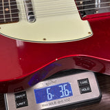 Red electric guitar on a digital scale displaying weight