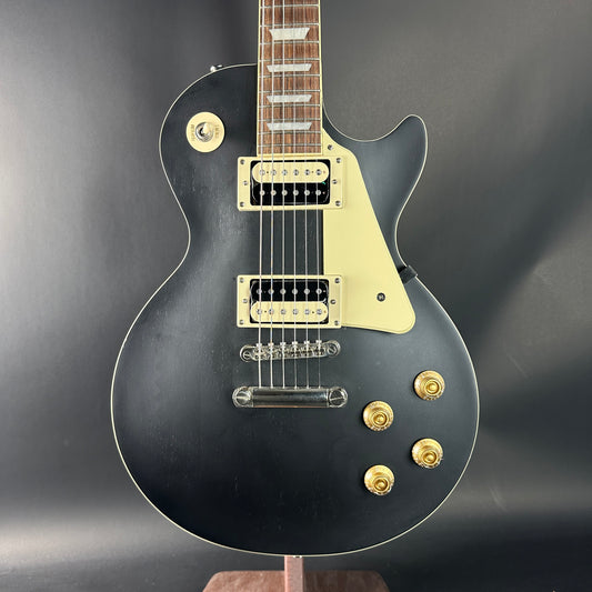 Black electric guitar with gold hardware on a dark background