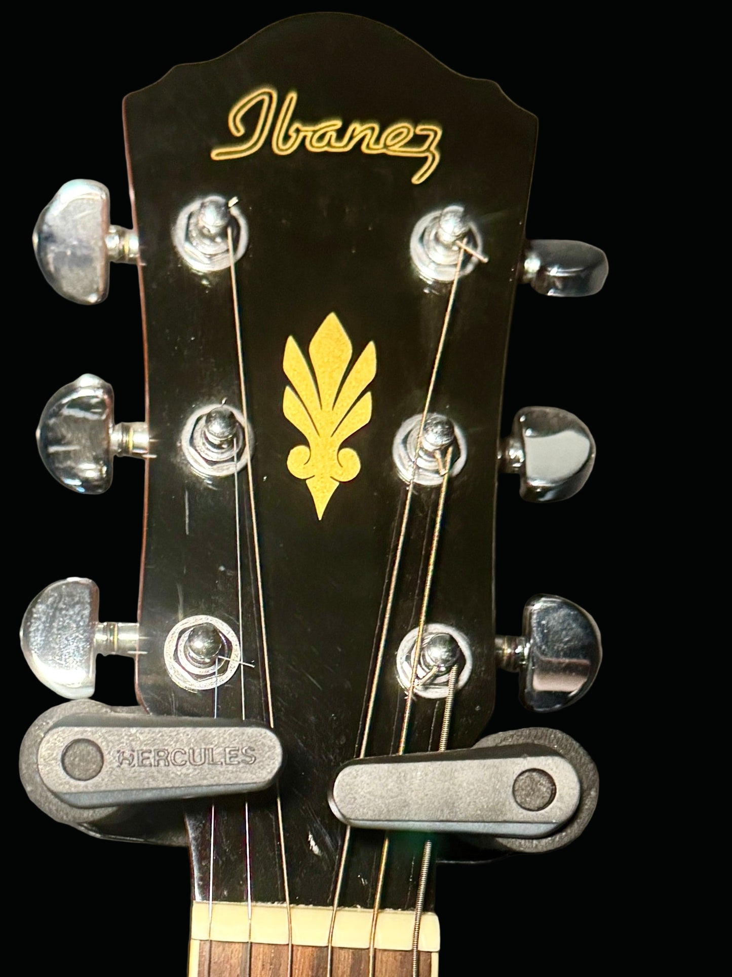 Ibanez guitar headstock with tuning pegs and logo on a gray background