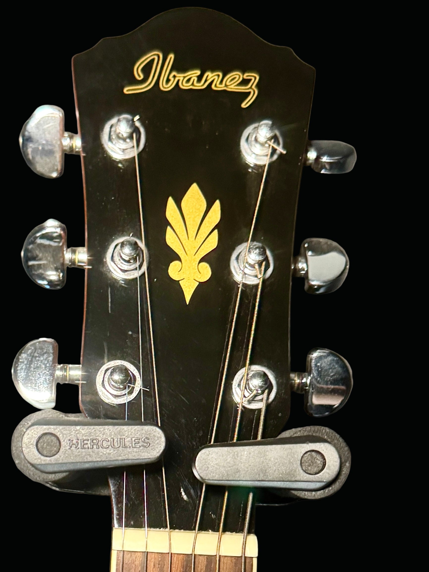 Ibanez guitar headstock with tuning pegs and logo on a gray background