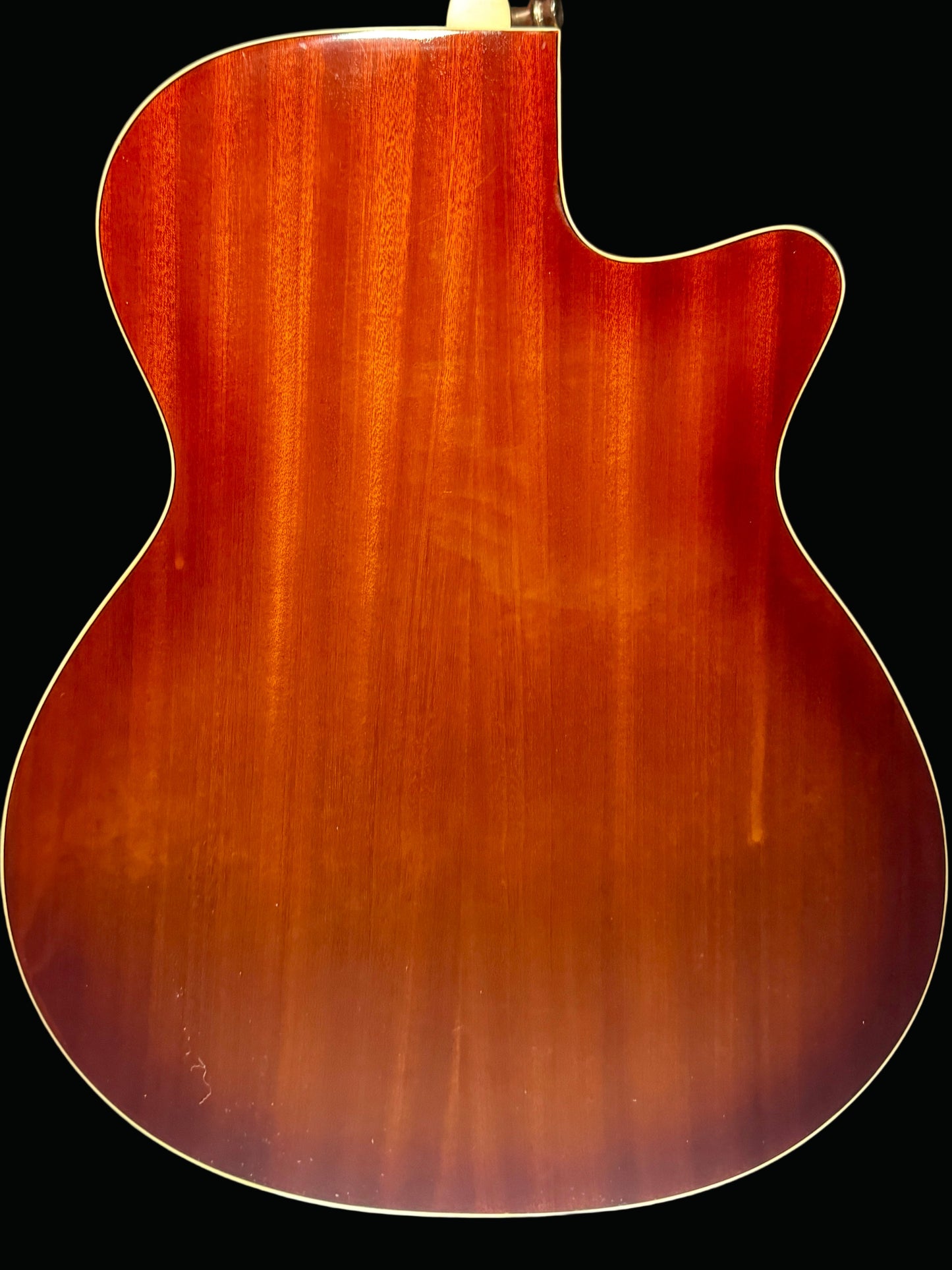 Back view of a wooden acoustic guitar on a dark background