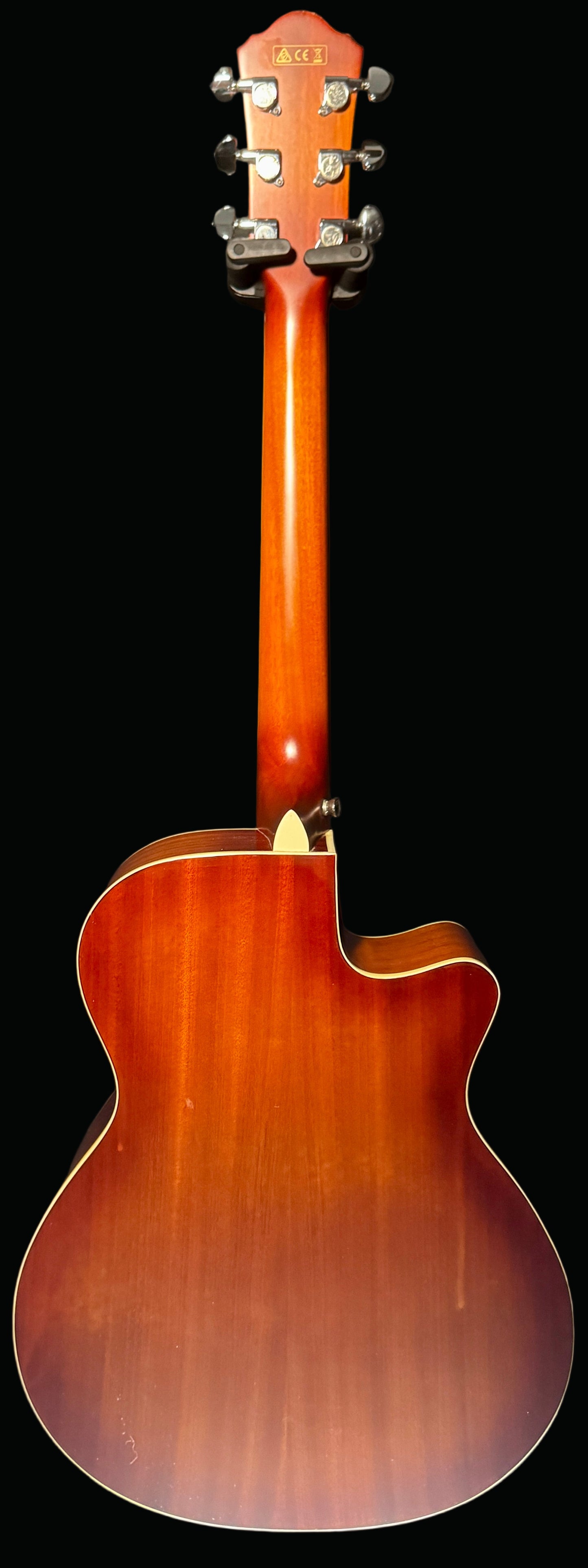 Back view of a wooden acoustic guitar on a dark background