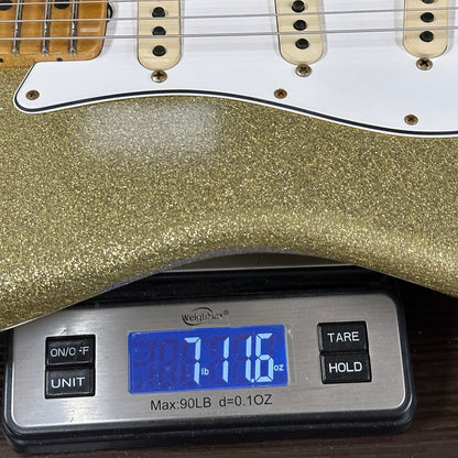 Gold glittery electric guitar on a digital scale displaying weight.