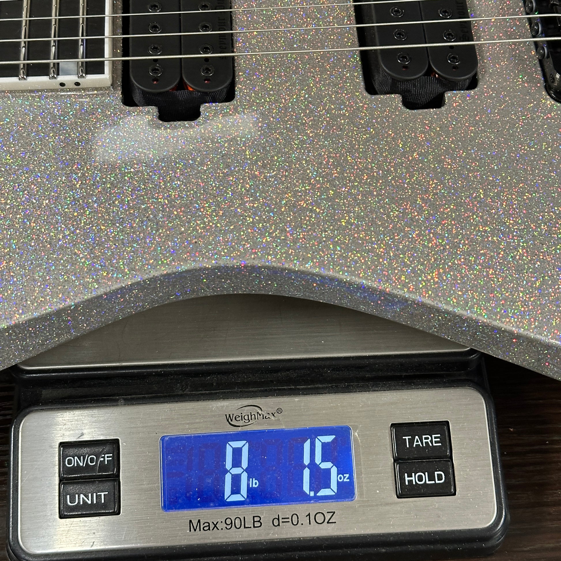 Silver glittery guitar on a digital scale displaying 8.5 ounces
