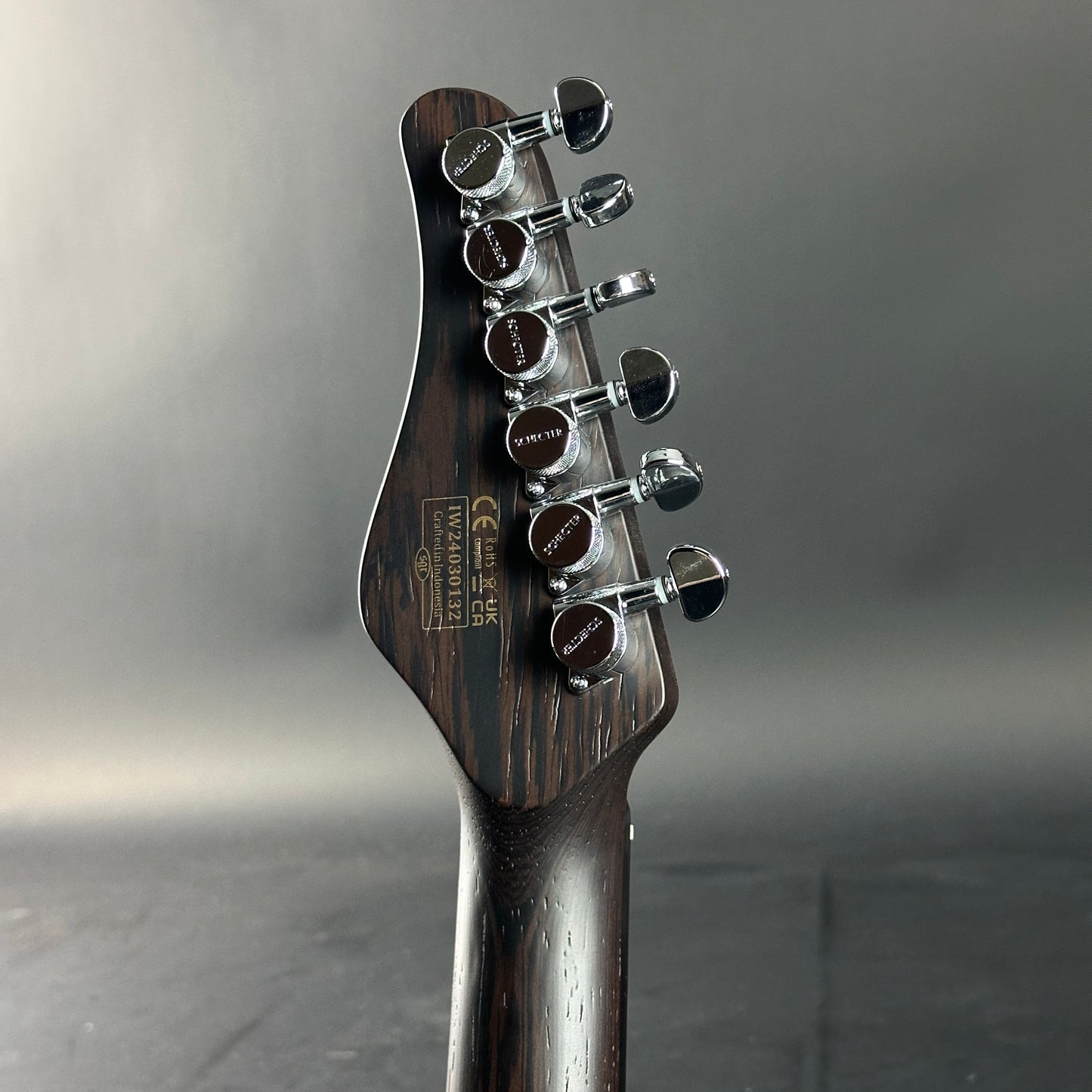 Guitar headstock with tuning pegs on a gray background