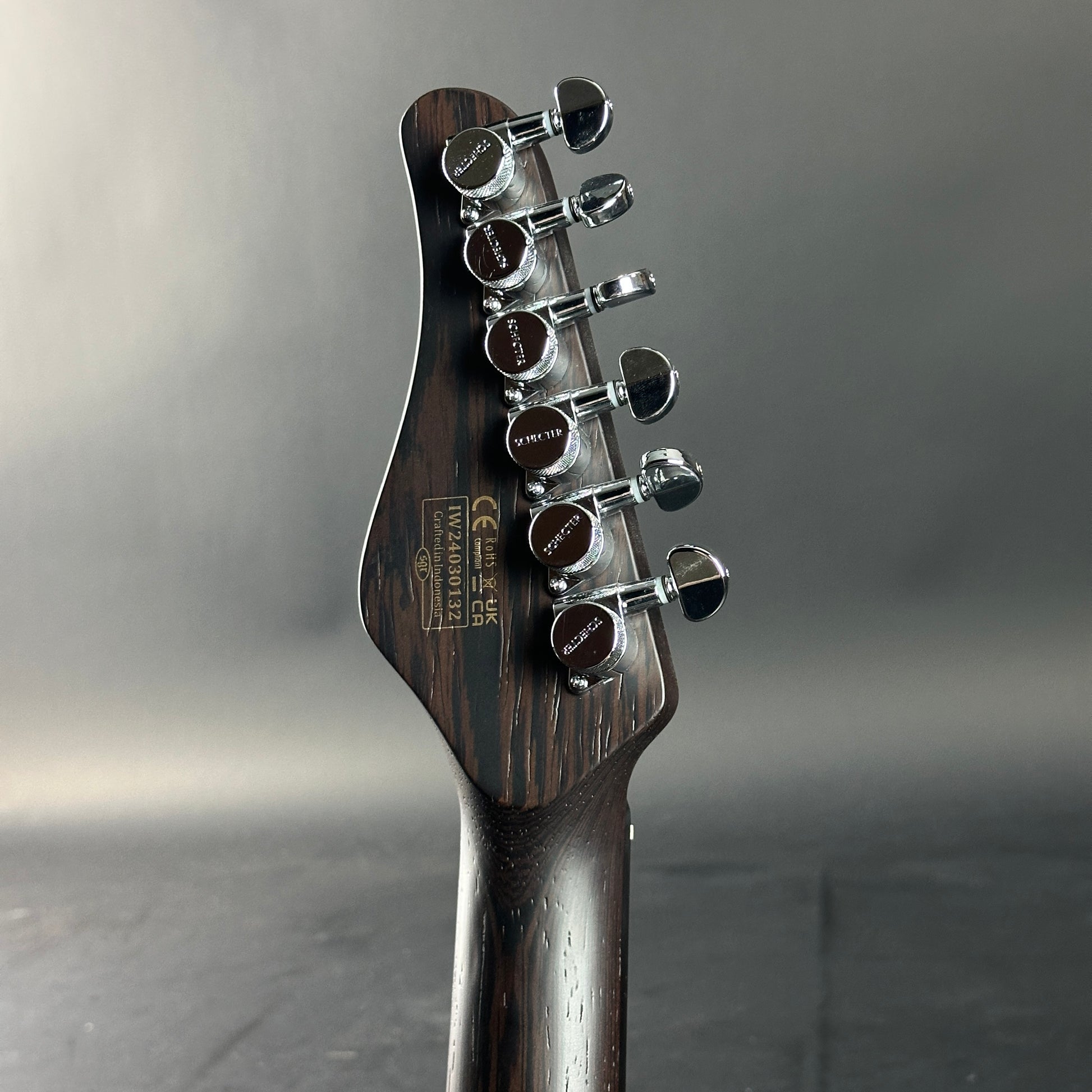Guitar headstock with tuning pegs on a gray background