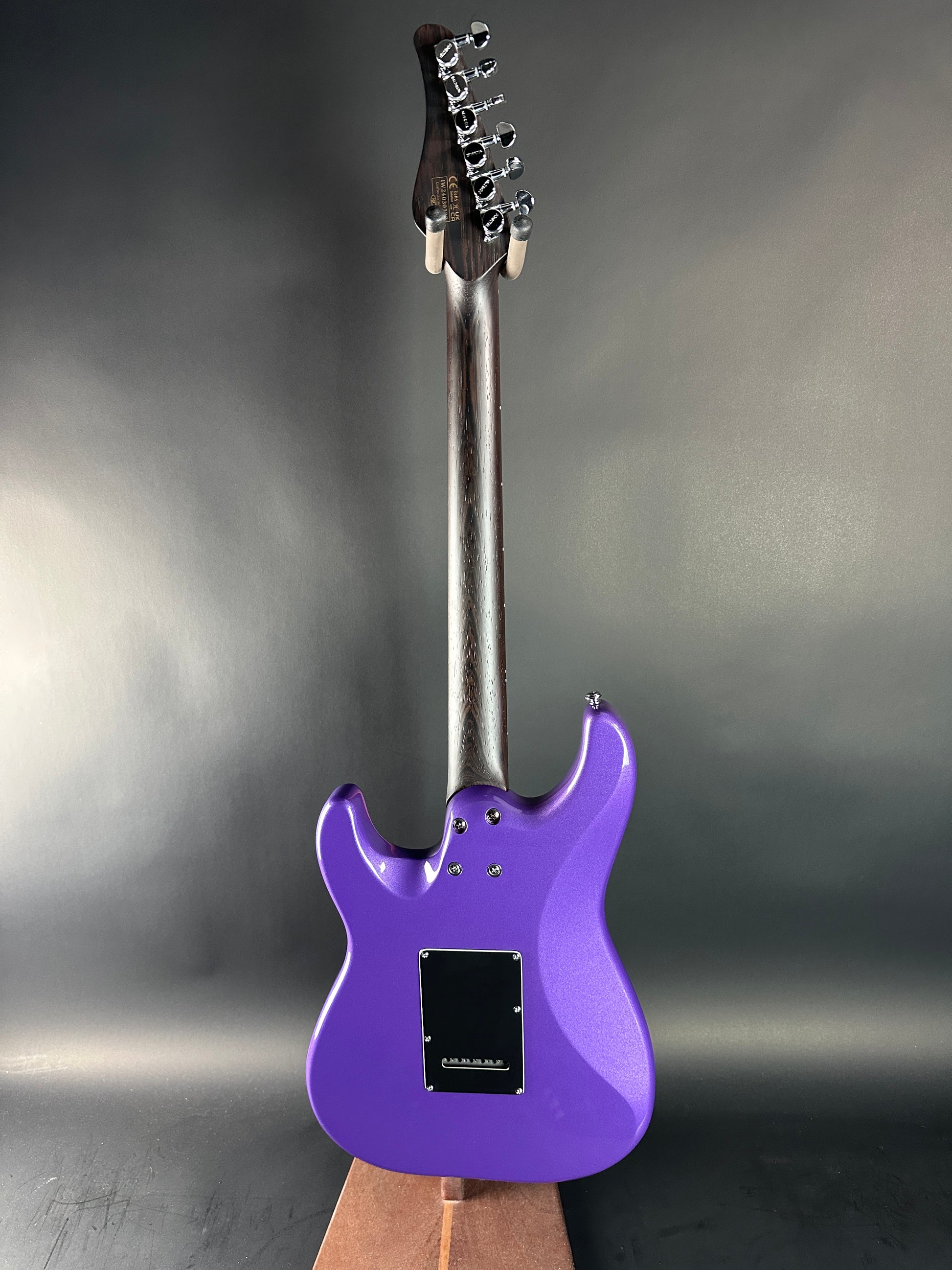 Purple electric guitar on a reflective surface with a gray background