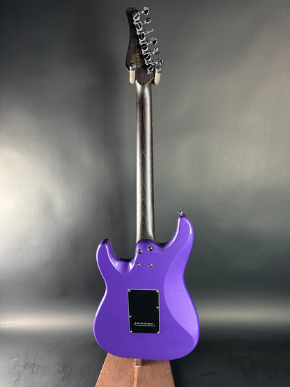 Purple electric guitar on a reflective surface with a gray background