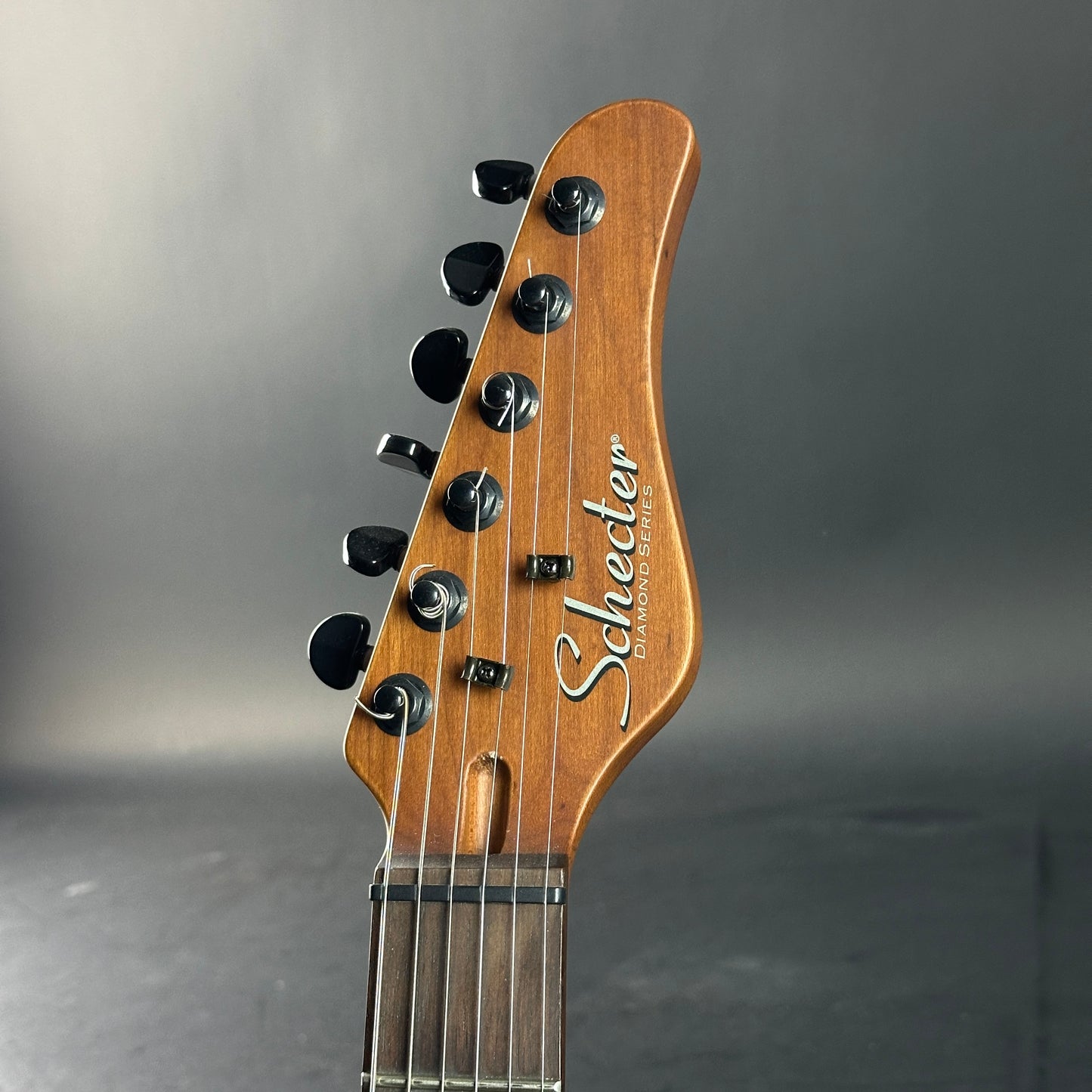 Guitar headstock with 'Schecter' branding on a gray background