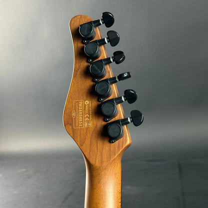 Close-up of a guitar headstock with tuning pegs on a gray background