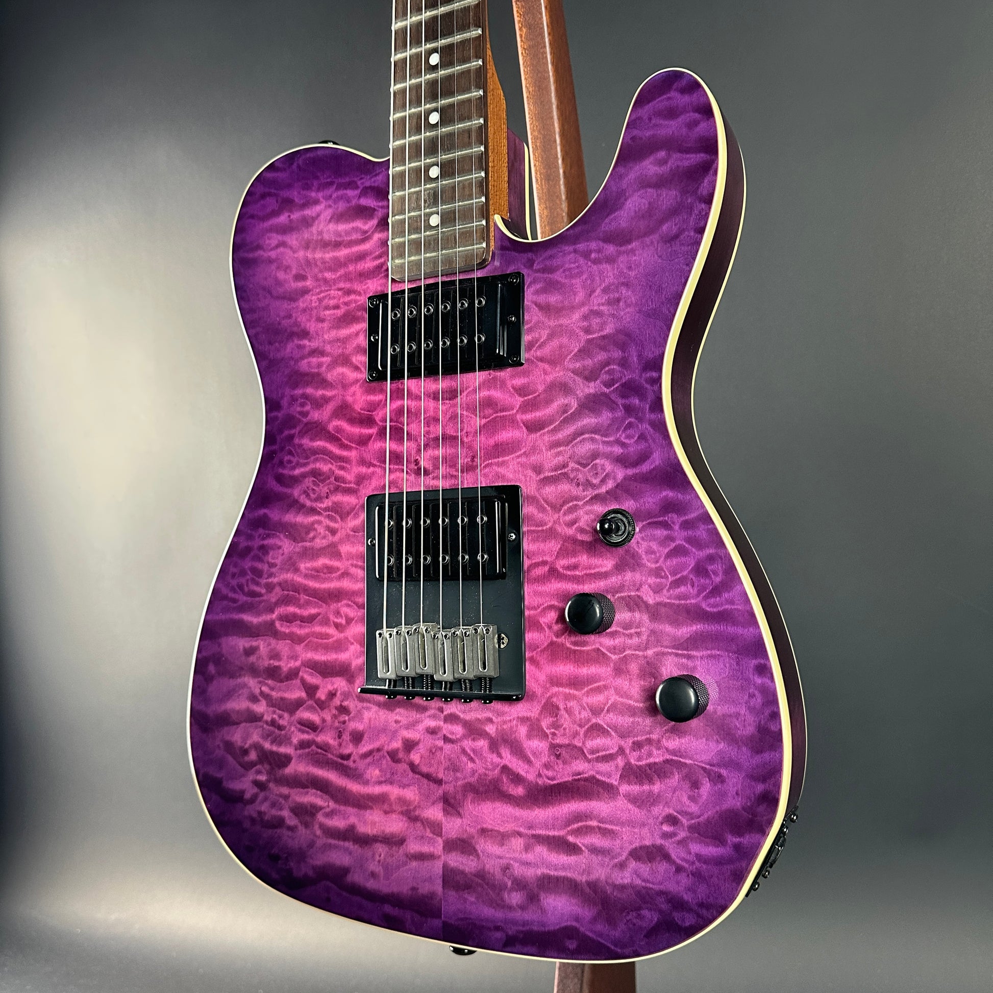 Purple electric guitar with a wavy finish on a gray background