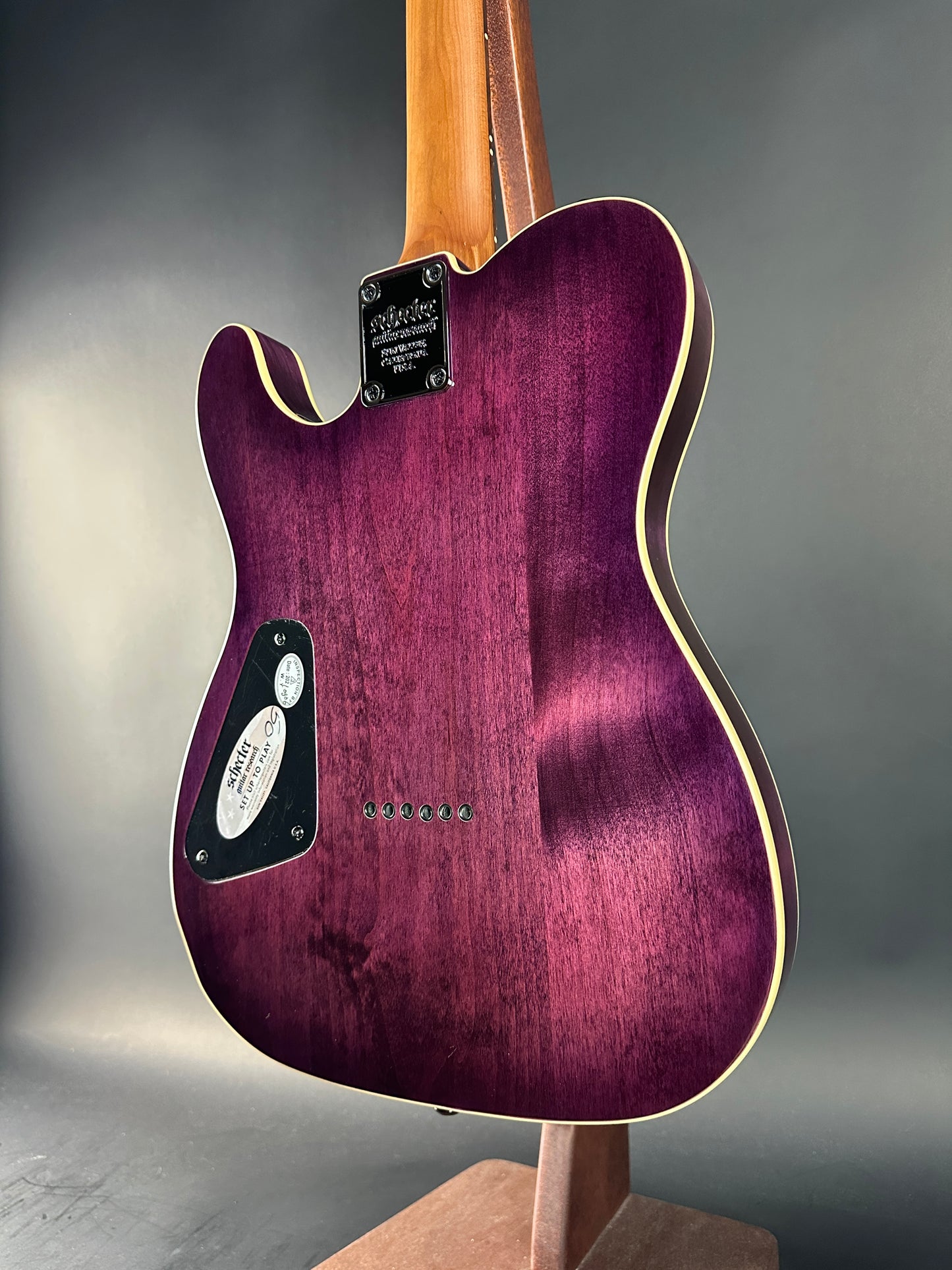 Purple electric guitar with a wooden neck on a gray background