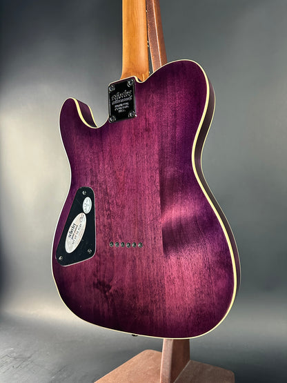 Purple electric guitar with a wooden neck on a gray background