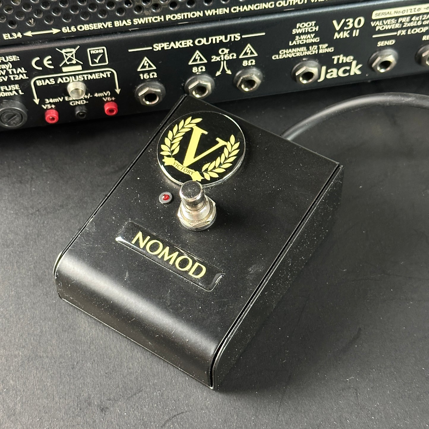 Black guitar pedal with 'Nomod' branding on a dark surface