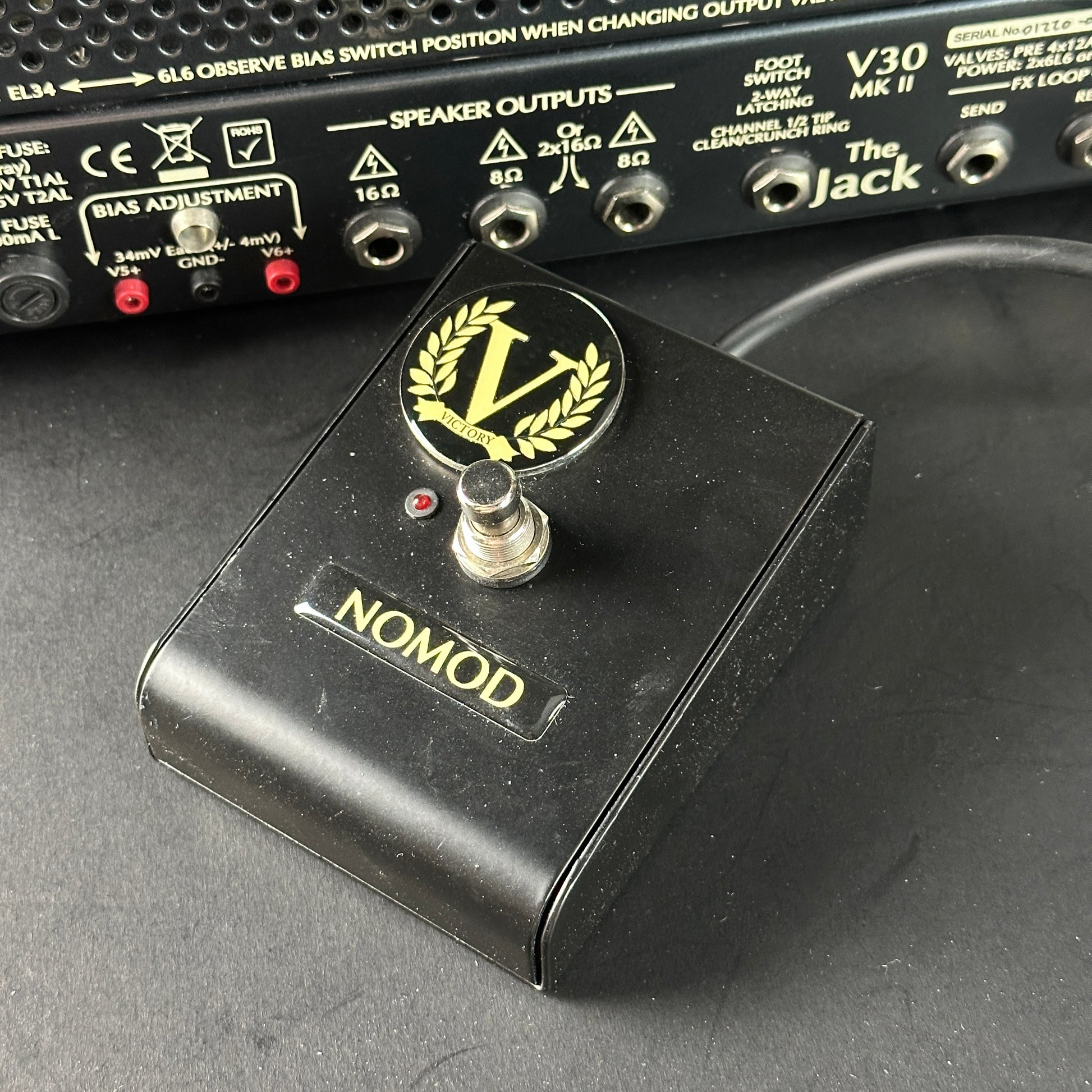 Black guitar pedal with 'Nomod' branding on a dark surface