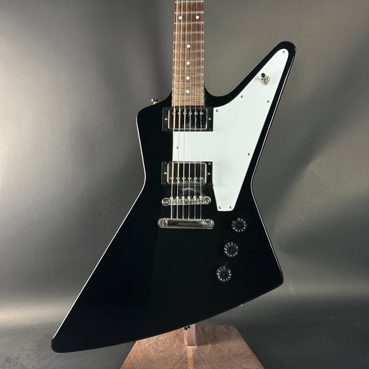 Black electric guitar with a white pickguard on a gray background