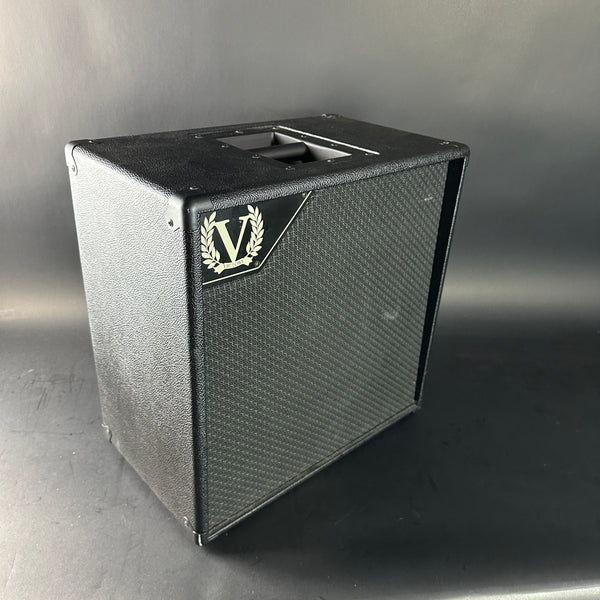 Black speaker cabinet with a logo on a gray background