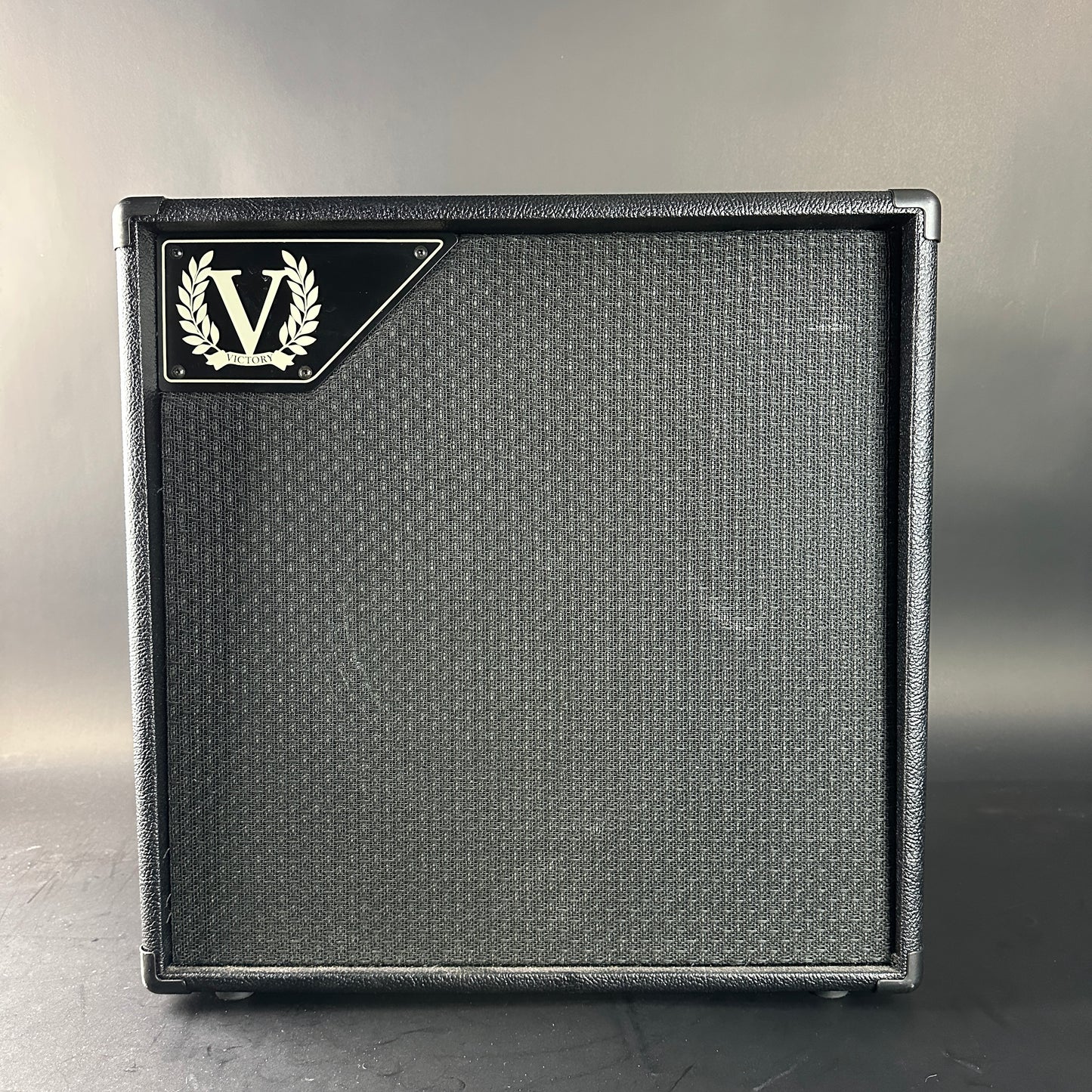 Guitar amplifier cabinet with a brand logo on a gray background