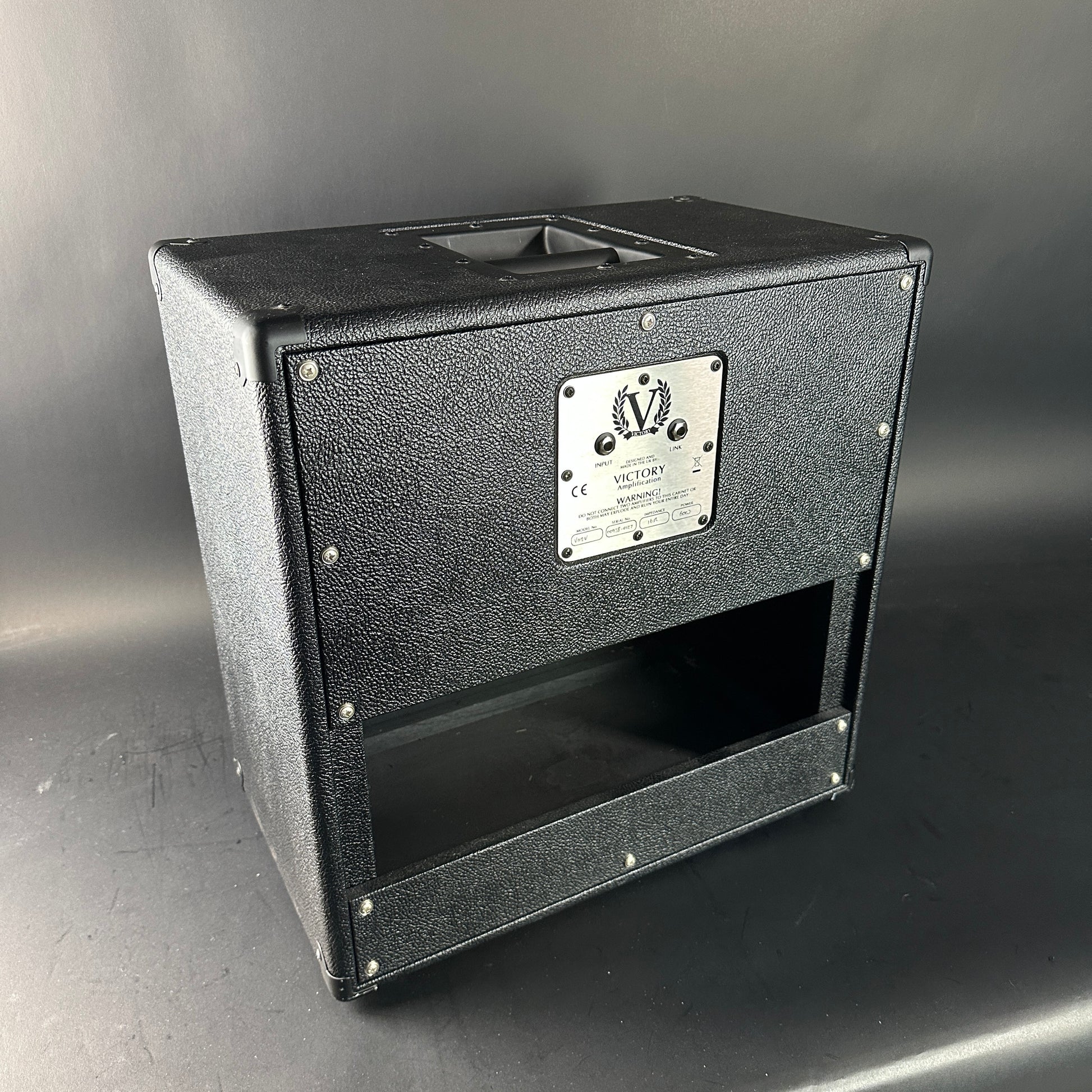 Black speaker cabinet with a brand label on a gray background