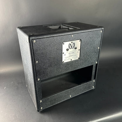 Black speaker cabinet with a brand label on a gray background