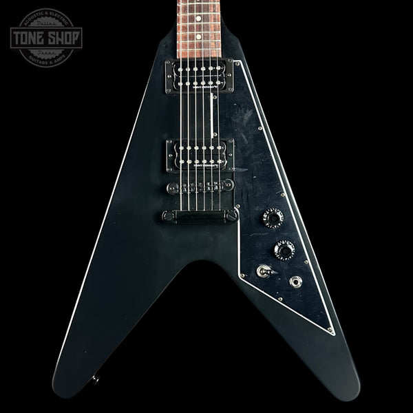 Black electric guitar with a unique design on a black background, featuring the 'Tone Shop' logo.