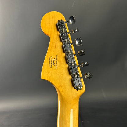 Guitar headstock with tuning pegs on a dark gray background