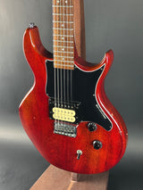 Red electric guitar on a gray surface with a blurred background
