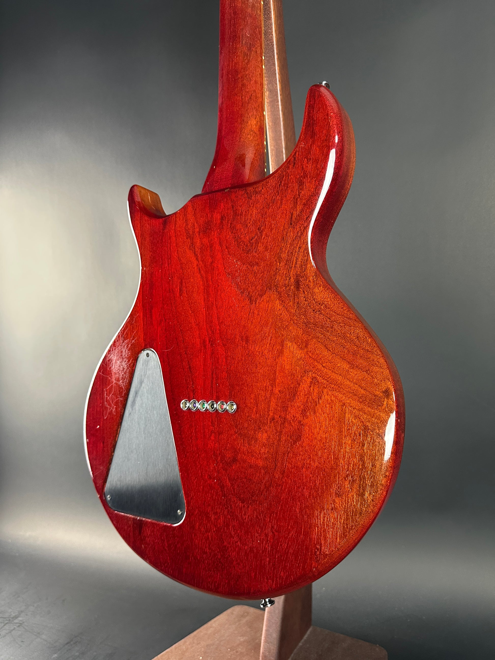 Close-up of a red electric guitar's body with a metallic finish on a gray background
