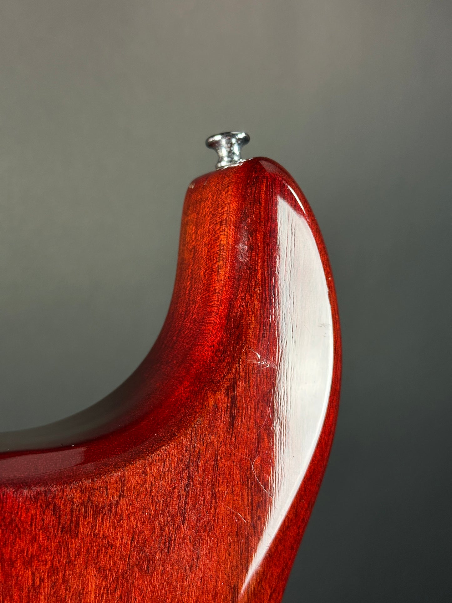 Close-up of a wooden handle with a metal screw on a gray background