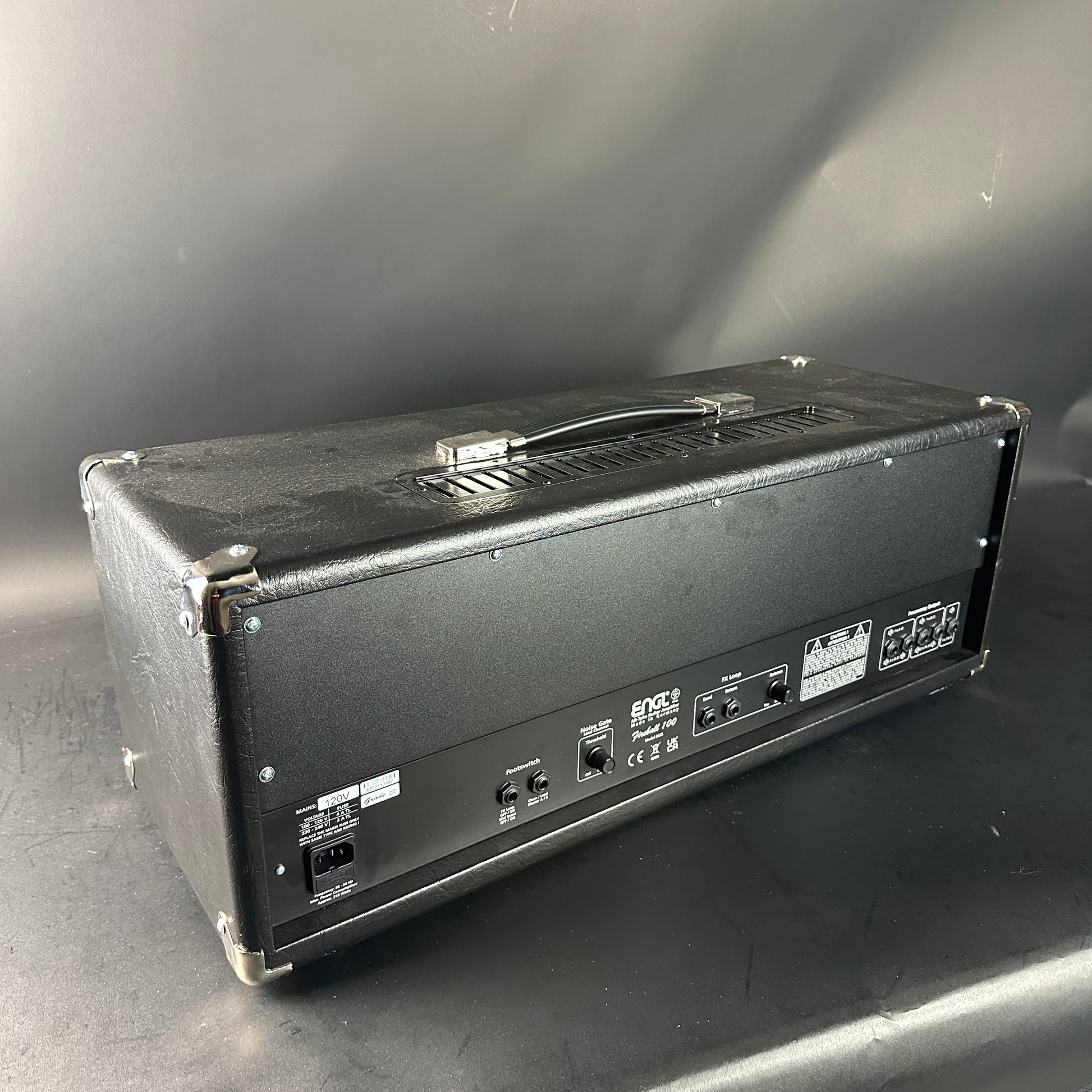 Back view of a guitar amplifier on a gray surface with a neutral background