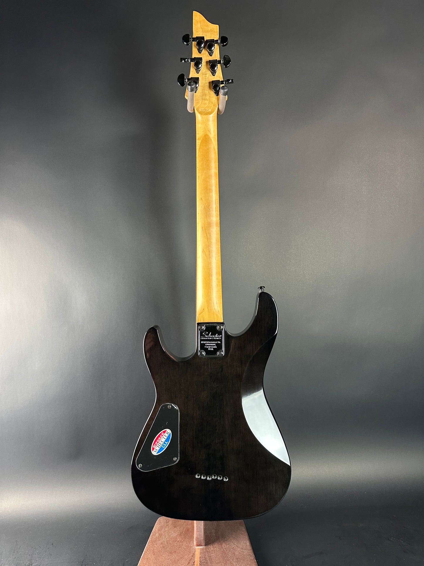Electric guitar with a black body and light wood neck on a gray background
