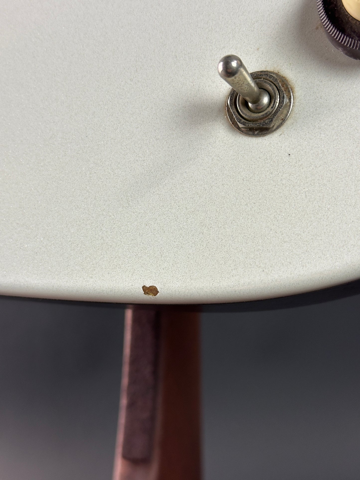 Close-up of a guitar switch on a white guitar body with a blurred background