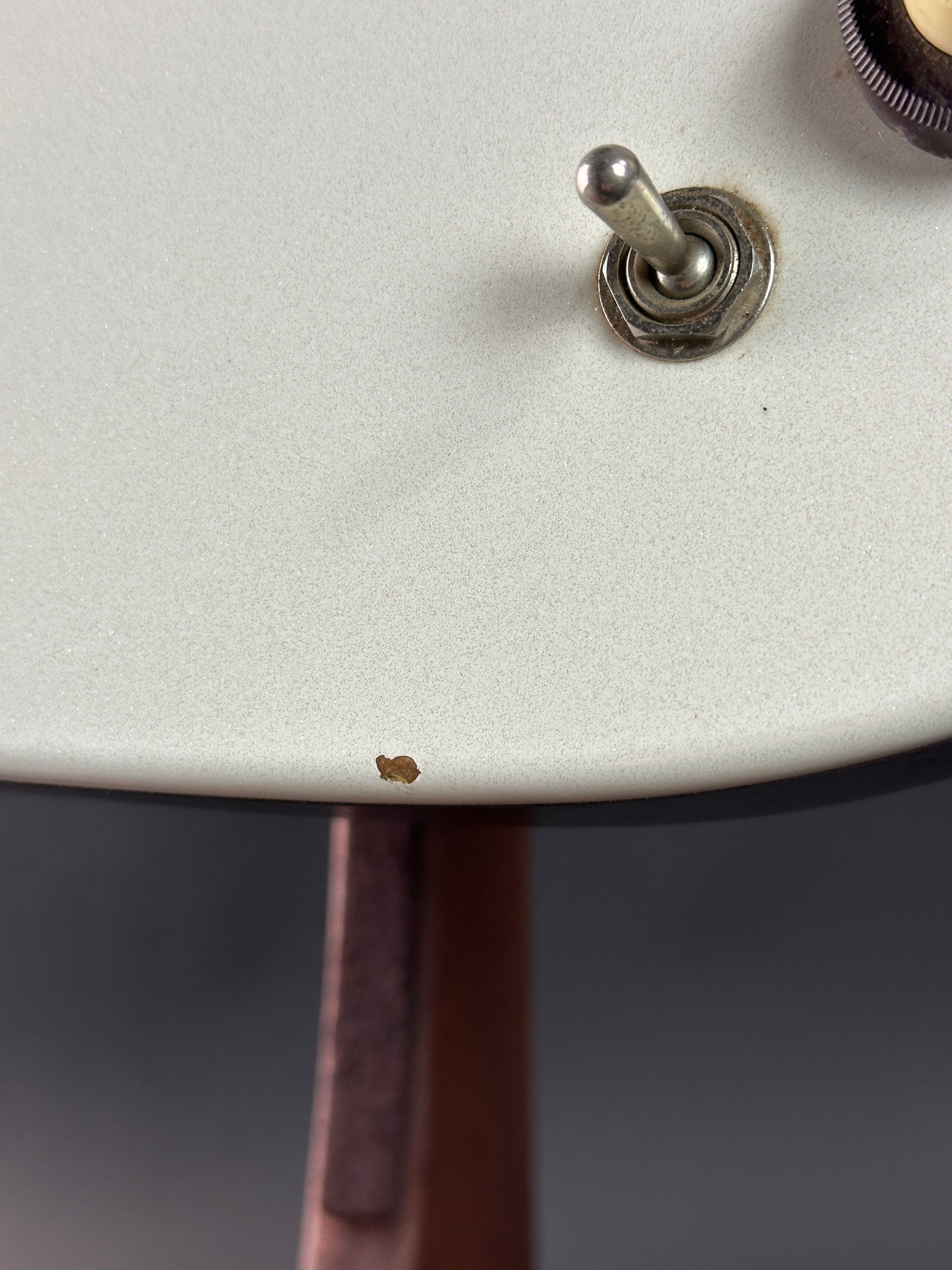 Close-up of a guitar switch on a white guitar body with a blurred background