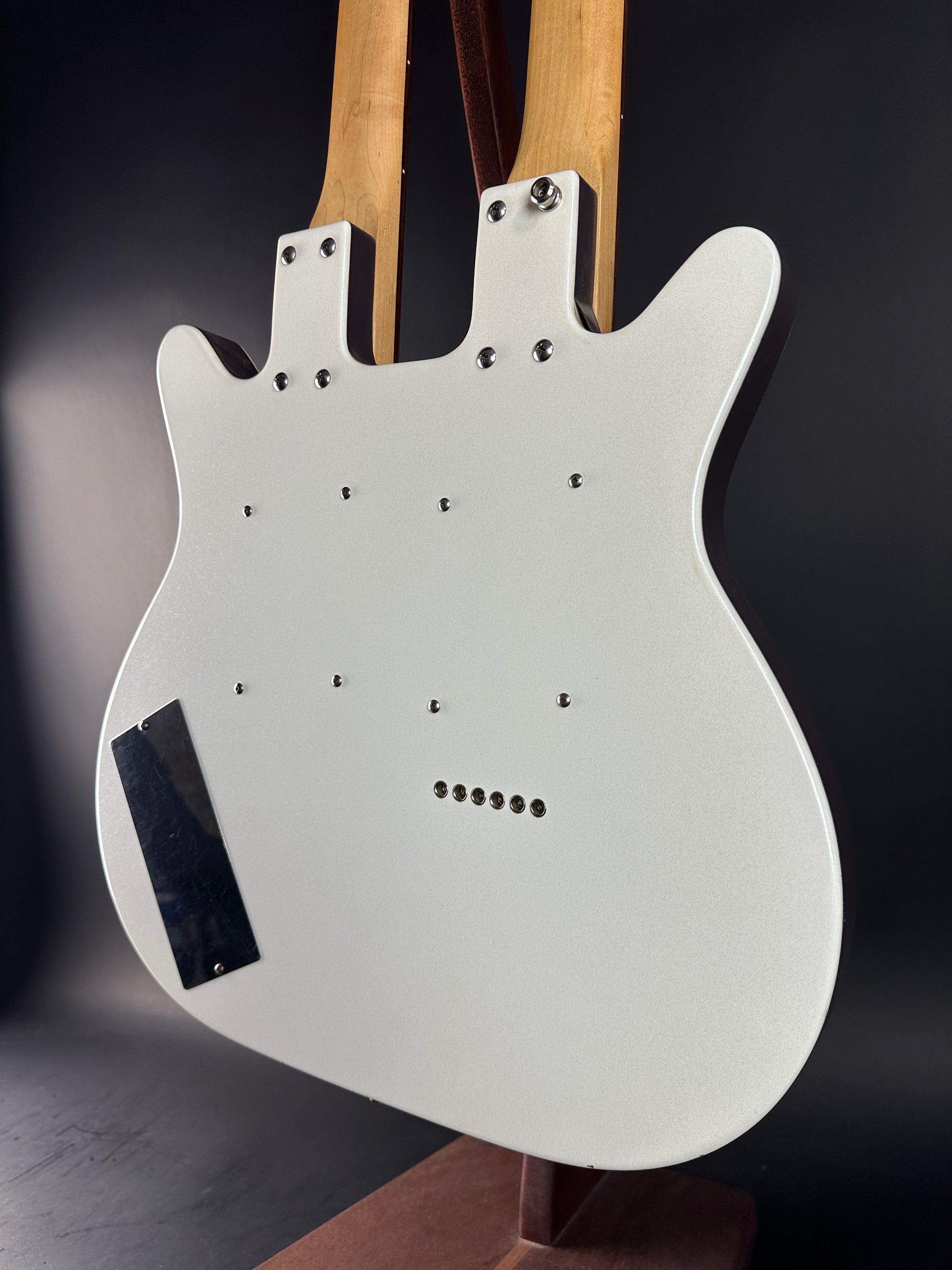 White electric guitar body with wooden fretboard on a dark background