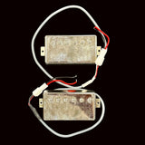 Two metallic guitar pickups with wires on a gray background