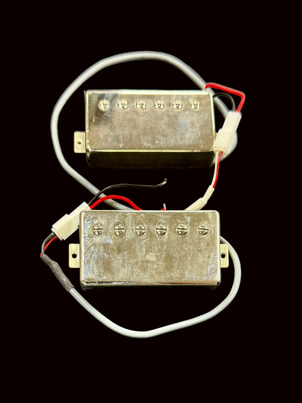 Two metallic guitar pickups with wires on a gray background