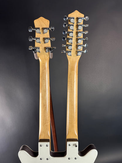 Two guitar necks with tuning pegs on a dark background