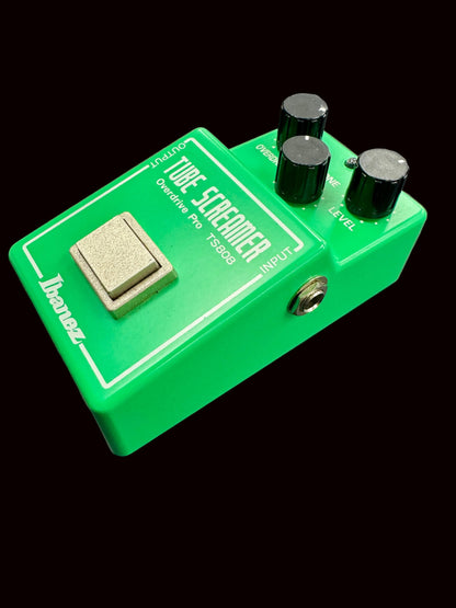 Green guitar effects pedal with knobs and switch on a gray background