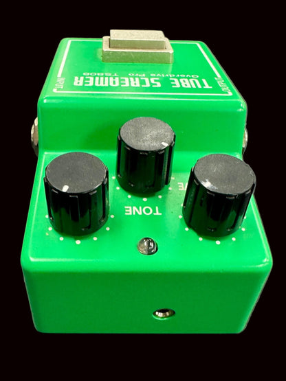 Green guitar effects pedal with black knobs on a gray background