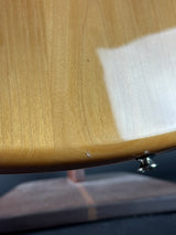 Close-up of a light natural wood grain surface with a glossy finish, showing a small metal screw fastener near the top edge and a dark background on the right.