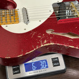 Red electric guitar on a digital scale displaying weight