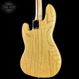 The back of a natural wood electric guitar, showing the glossy grain of the maple body, neck, and headstock against a solid black background.