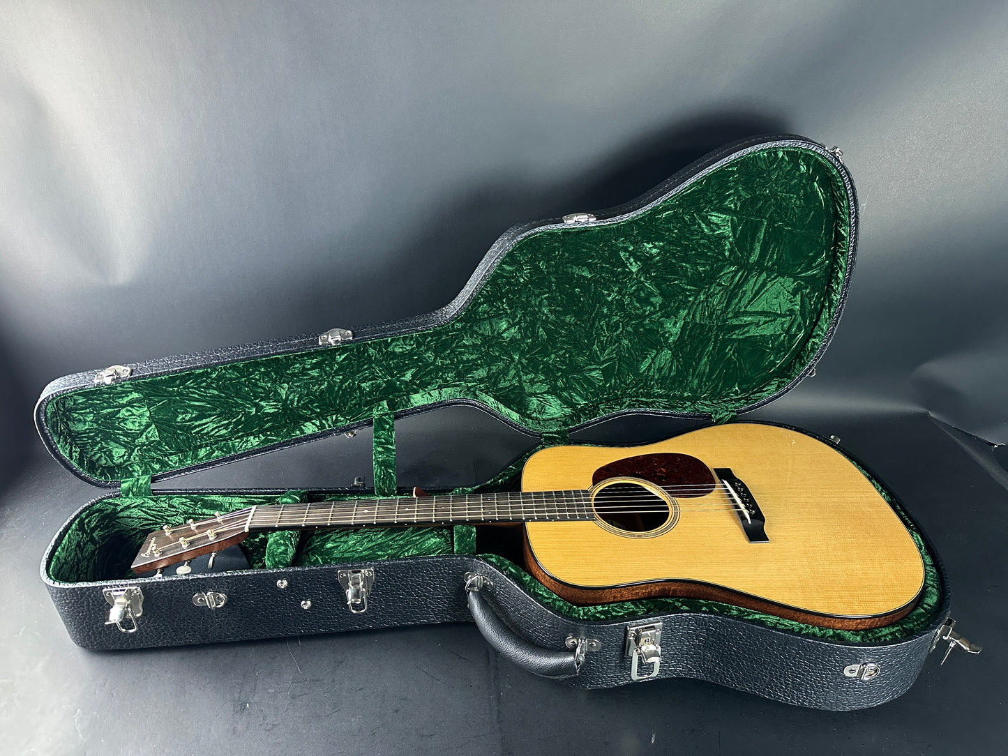 Acoustic guitar in a green and black case on a gray background
