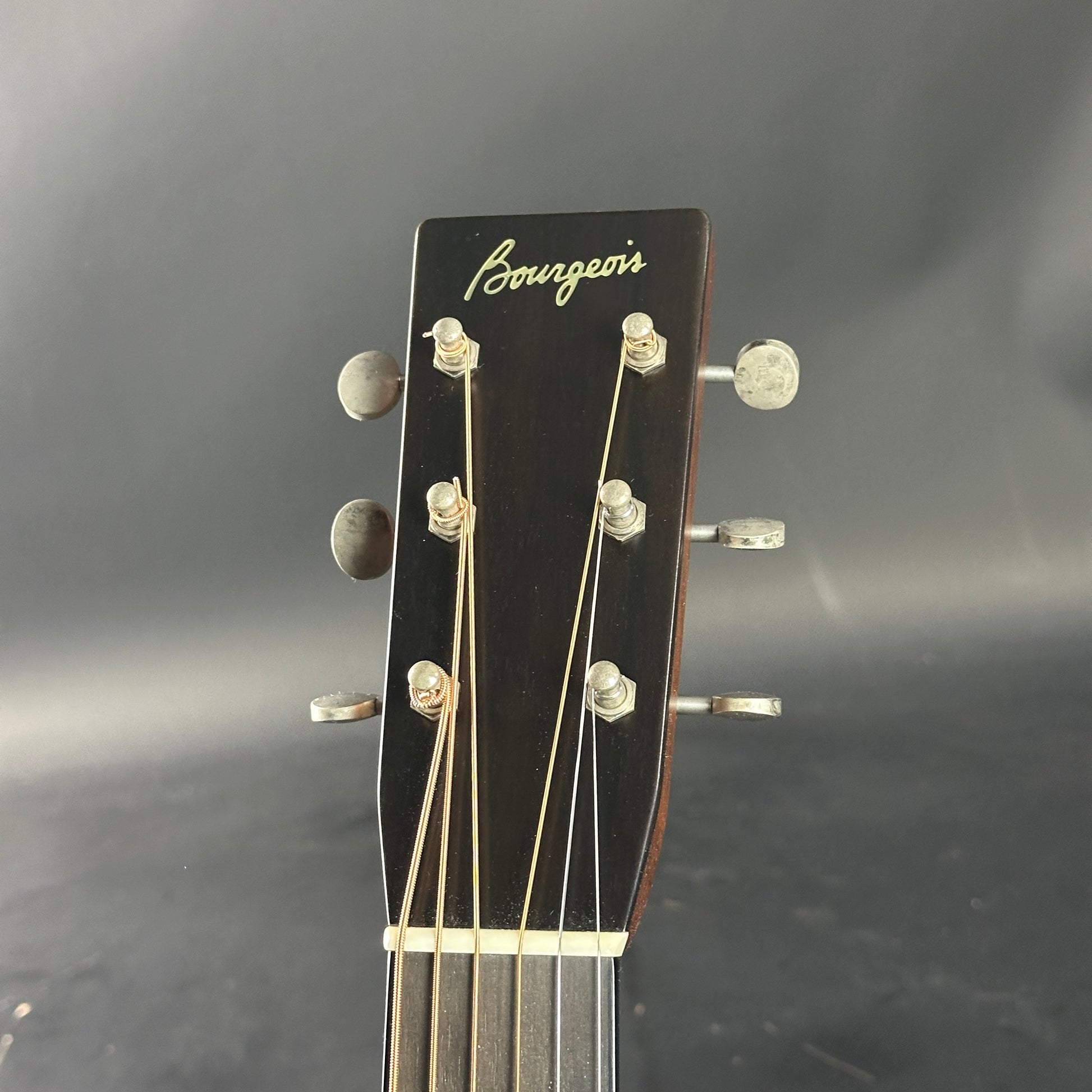 Guitar headstock with 'Bourgeois' branding on a dark background