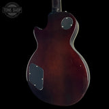 The back of a dark brown electric guitar with a glossy finish, shown against a solid black background. A Tone Shop watermark is visible in the top-left corner.