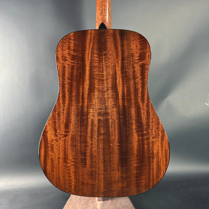 Back view of a wooden acoustic guitar on a gray background