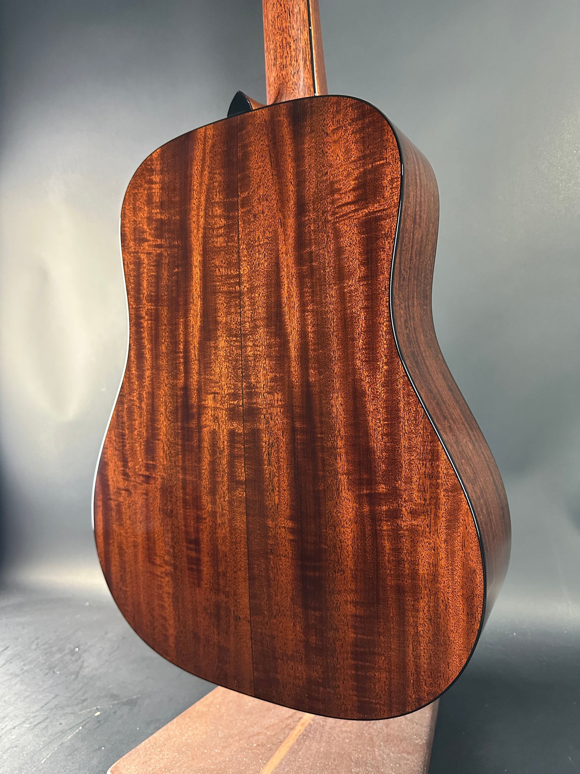 Close-up of a wooden acoustic guitar body on a gray background
