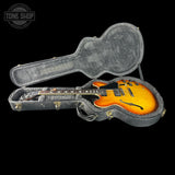 Electric guitar in a hard-shell case with 'Tone Shop' branding.