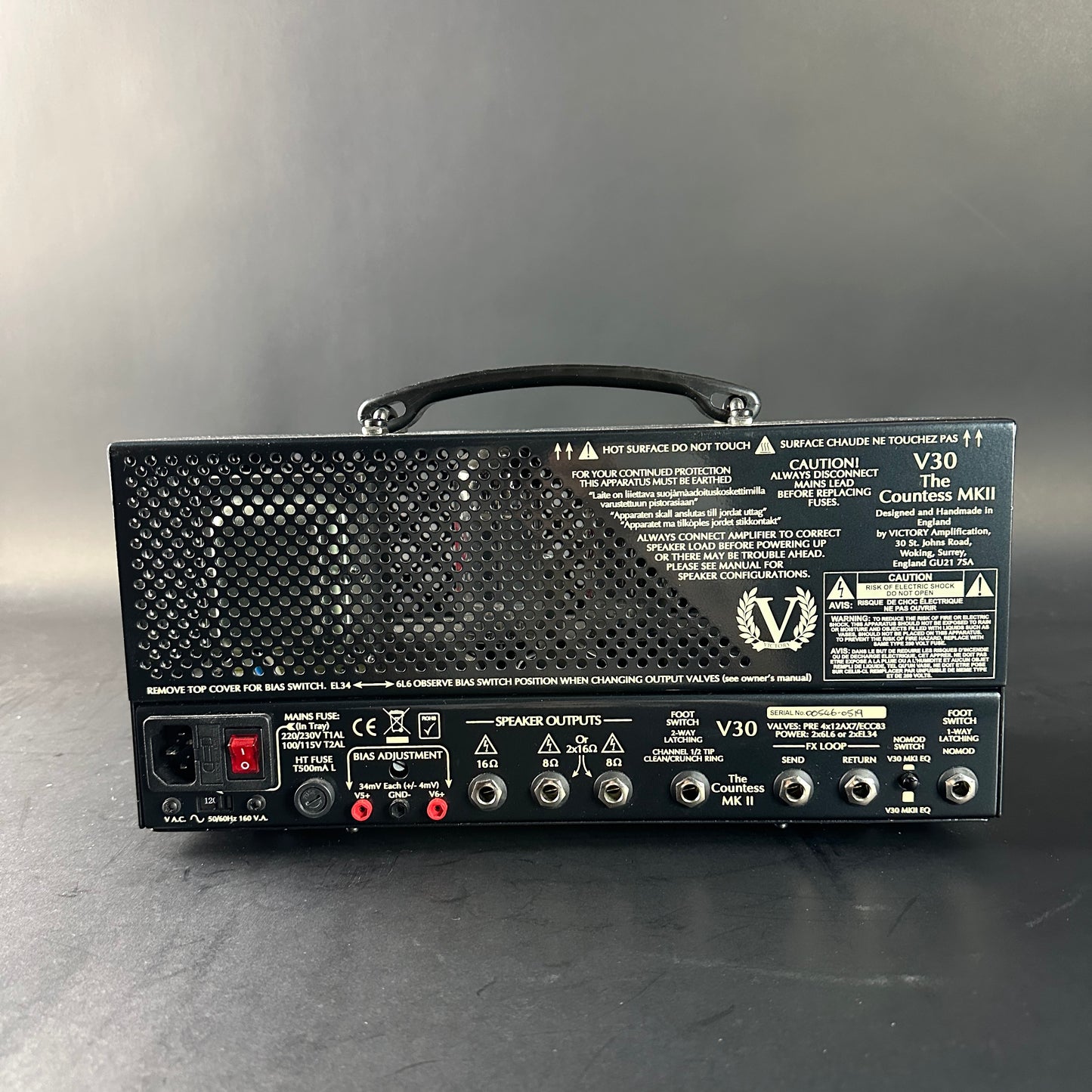 Back view of a black amplifier with various controls and labels on a gray background