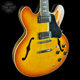 Electric guitar with a sunburst finish on a black background, featuring the Tone Shop logo.